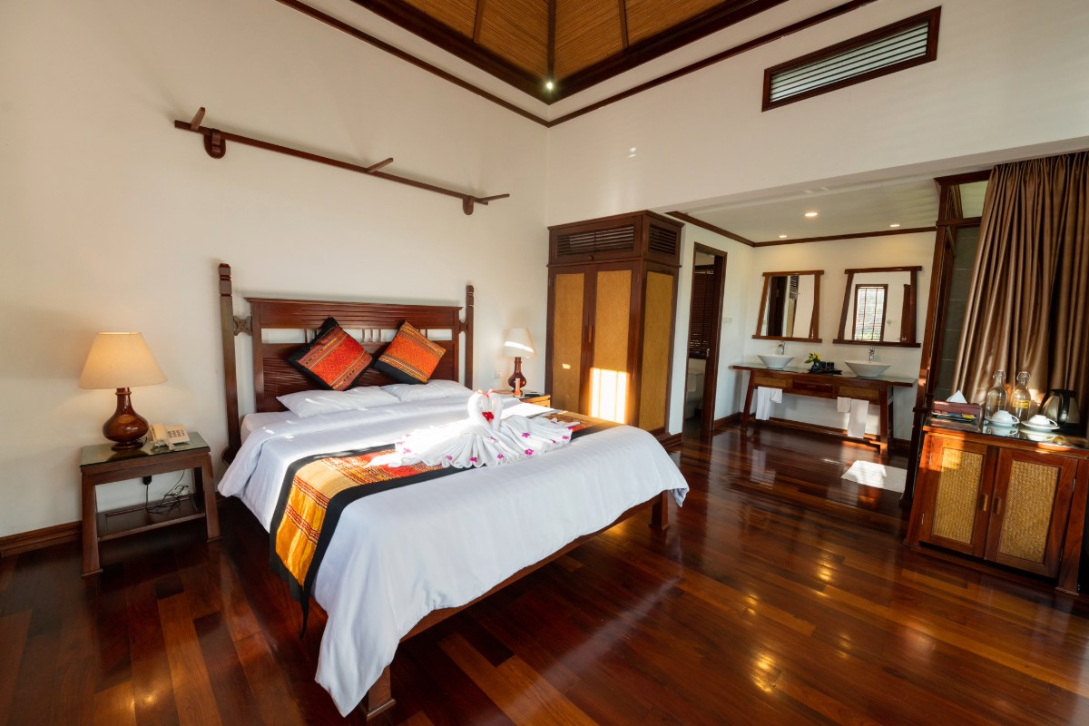 Sleeping area of the luxury suite at Le Grand Pakbeng with double bed and wooden furniture